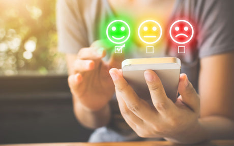 Woran erkennt man gute Qualität mei Fitnessgeräten - Frau bewertet via Smartphone ein Produkt positiv